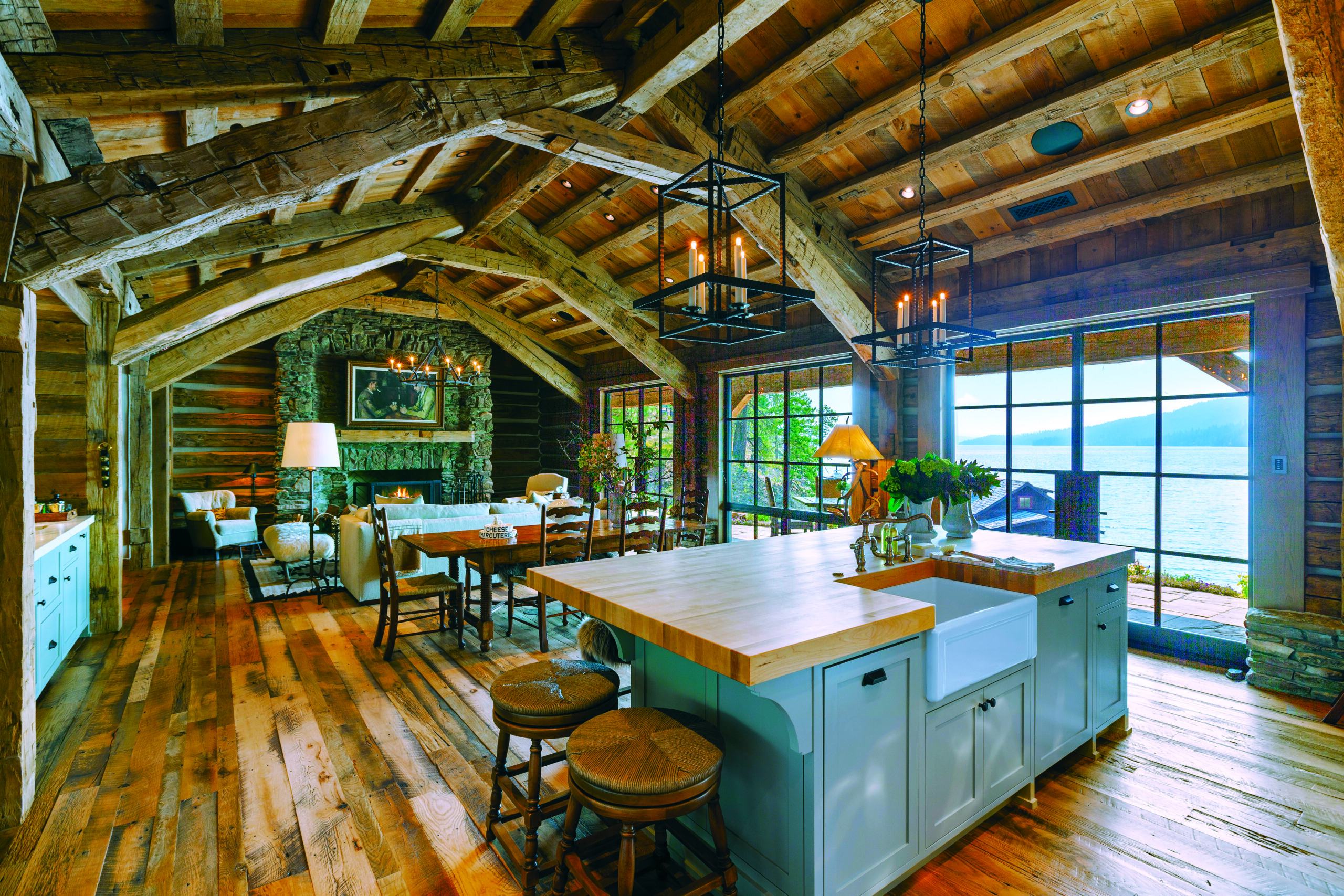 The layout flows between the kitchen, dining and living rooms. Patches of moss and lichens remain on the Montana moss- rock fireplace for an instantly aged look. Vintage finds include the dining table and chairs the homeowner bought at a secondhand store. | Photo: Mike McCall