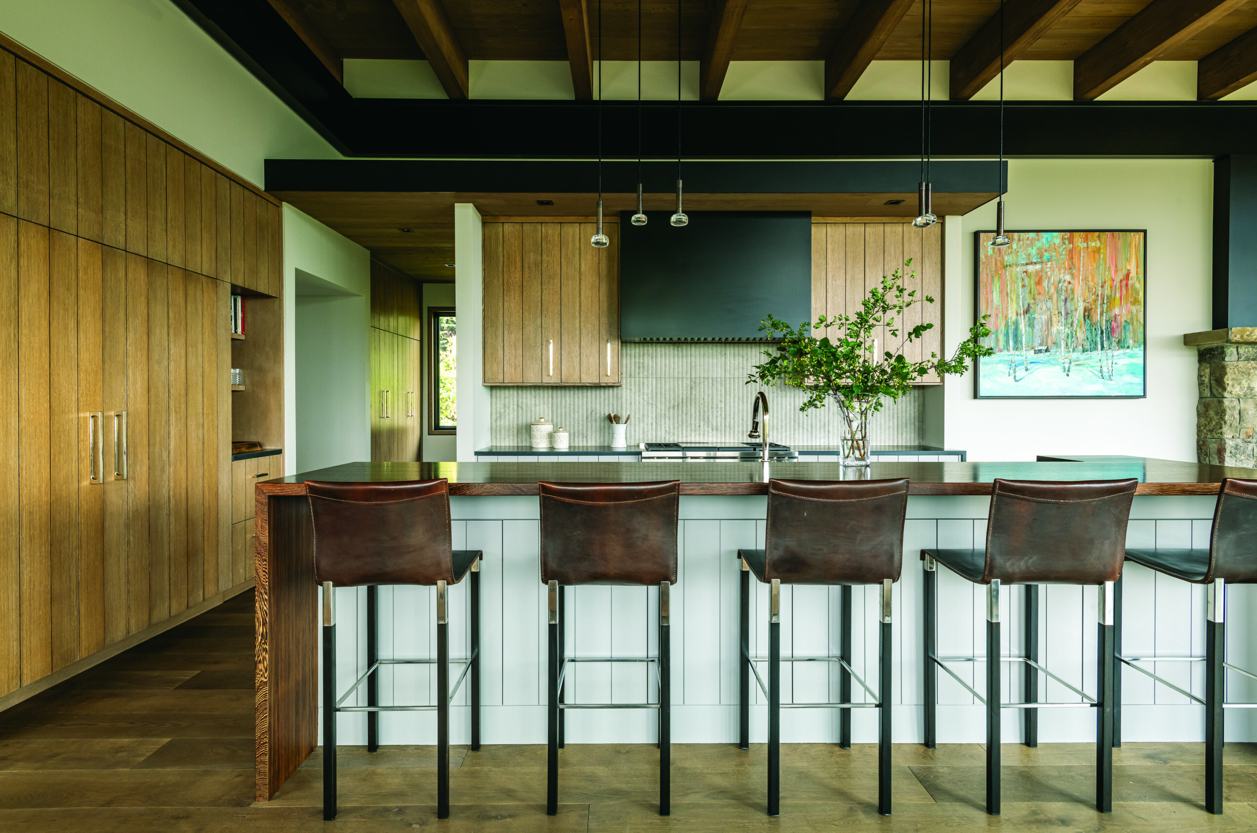 A mix of finishes in the kitchen including a wenge- topped island, white-oak cabinetry and a Pannelli marble backsplash lend an air of refined rusticity to the kitchen. The designer added leather stools to further the natural flavor. | Photo: Audrey Hall